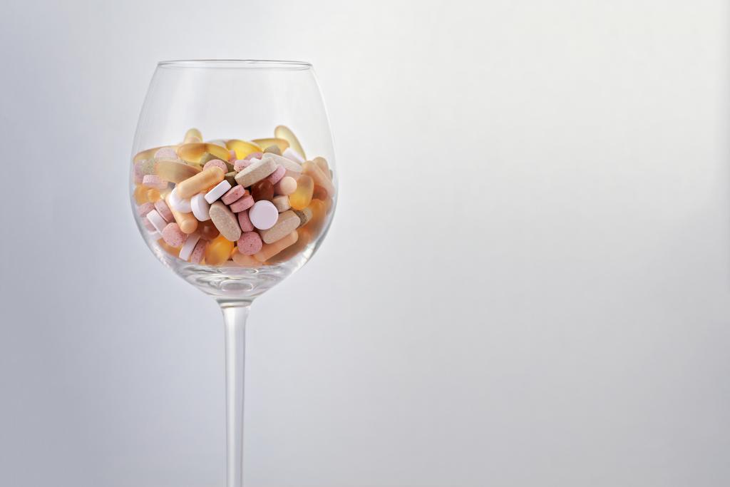 Tablettencocktail verschiedener Schlaftabletten und Psychopharmaka in einem Weinglas.